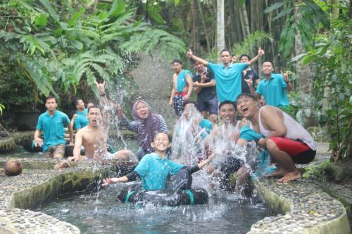 Eine Gruppe von Menschen, die um einen Brunnen herum sitzen in der Unterkunft Villa Kampung Ayem Riverside in Sleman