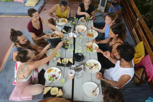 een groep mensen die rond een tafel eten bij GoYm Resort in Arambol