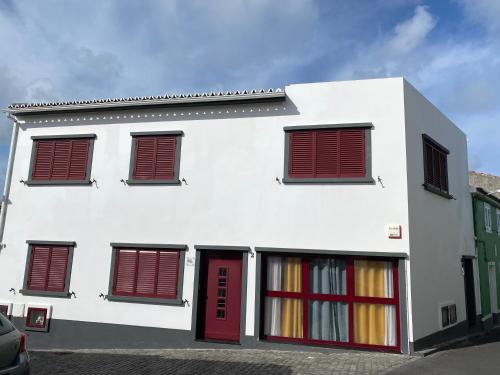 un edificio blanco con persianas rojas. en Santa Luzia Apt I, en Ribeira Grande