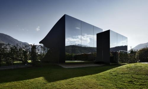 um grande edifício de vidro com montanhas ao fundo em Mirror Houses em Bolzano