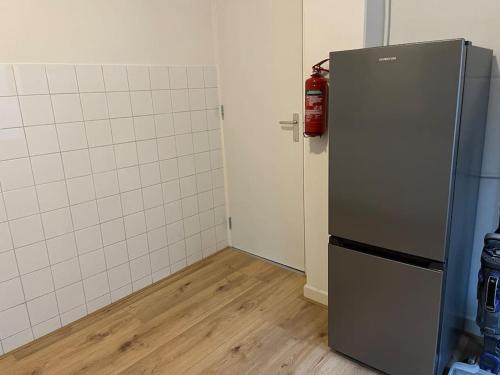 y cocina con nevera. un extintor de incendios en Appartement centrum Leeuwarden, en Leeuwarden