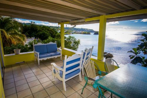 een veranda met stoelen en een tafel en uitzicht op het water bij Casa del Vega a Little Peace of Heaven in Castries