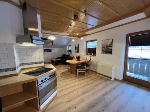 uma cozinha e sala de estar com um fogão e uma mesa em apartment Eva in Wald im Pinzgau with balcony em Wald im Pinzgau