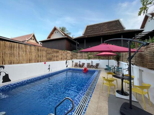 - une piscine avec des chaises et un parasol rose dans l'établissement Little Friendly Guest House and Swimming Pool, à Luang Prabang