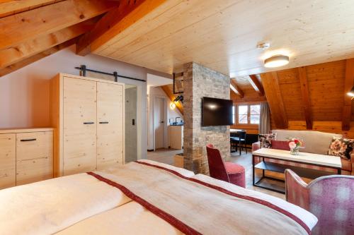 een slaapkamer met een groot bed in een kamer met houten plafonds bij Sonne Andermatt Swiss Quality Hotel in Andermatt