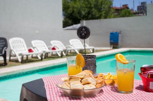 - une table avec une assiette de pâtisseries et deux verres de jus d'orange dans l'établissement Apart Porto del Sol by CPH, à Villa Carlos Paz