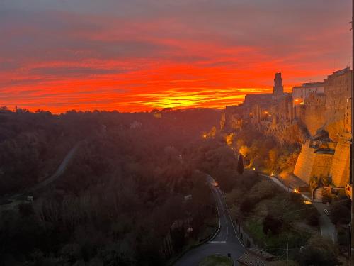 einen Sonnenuntergang über einer Stadt mit einem Gebäude und einer Straße in der Unterkunft Affittacamere Licenza N.1 Presso La Magica Torre in Pitigliano