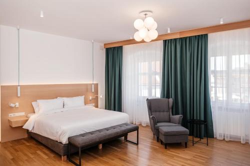 a bedroom with a bed and a chair at Hotel Casa Luxemburg- Newly Renovated in Sibiu