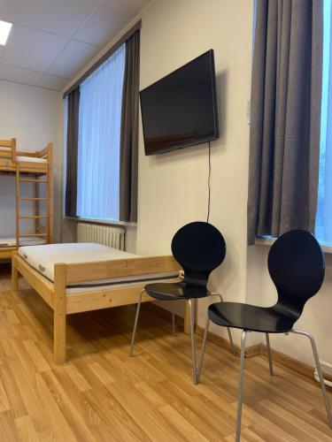 una camera con un letto e due sedie e una TV a schermo piatto di Central Hostel Jelgava a Jelgava