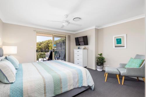 een slaapkamer met een bed, een stoel en een raam bij Aqua Lagoon - Great Family Beach Getaway in Nelson Bay