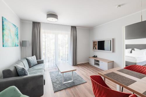 sala de estar con sofá y cama en Sporthotel Neuruppin - Apartmenthaus mit Ferienwohnungen, en Neuruppin