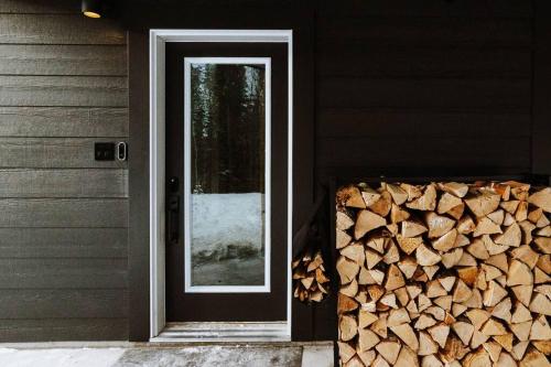 eine Tür zu einem Haus mit einem Haufen Feuerholz in der Unterkunft Okt Häus in Nordegg