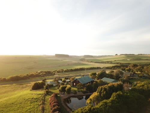 - une vue aérienne sur une ferme avec une maison et une rivière dans l'établissement Daysy Hill Country Cottages, à Port Campbell