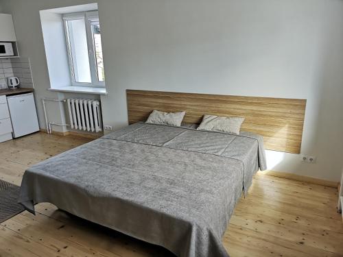 - une chambre avec un grand lit et une tête de lit en bois dans l'établissement COMFY Patogūs namai, à Kaunas