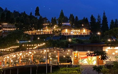 un grand bâtiment éclairé la nuit avec des lumières dans l'établissement Alinson Sunset Hill, à Bogor