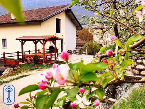 ein Gebäude mit einem Pavillon und rosa Blumen in der Unterkunft Casa Vacanze Antico Eremo, tra natura e tradizione in Campodenno