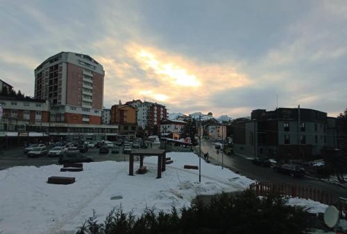 a city with a snow covered parking lot with buildings at 4Seasons appartamenti in Sauze dʼOulx