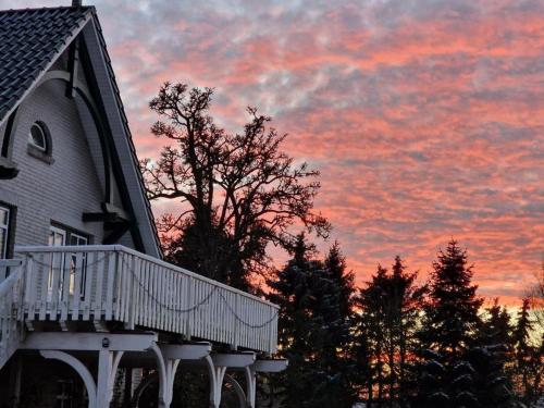 una casa con una terraza con una puesta de sol en el fondo en Schleiblick im Andersenhof, en Kappeln