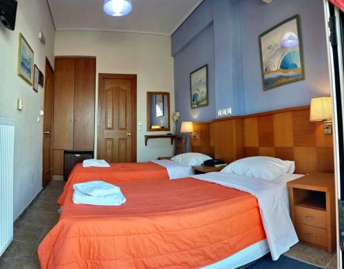 ein Hotelzimmer mit 2 Betten mit orangefarbener Bettwäsche in der Unterkunft TARLAS ROOMS in Mytilini