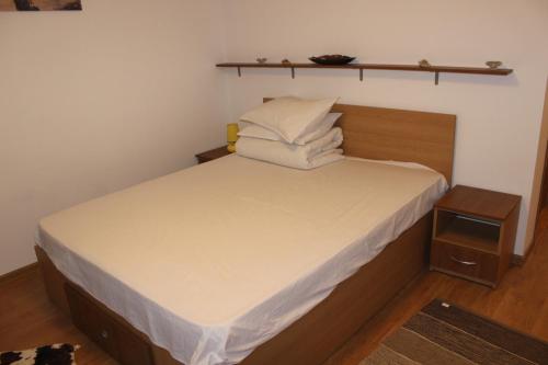 a small bedroom with a bed with white sheets and pillows at Pensiunea Martinel in Timisu de Sus