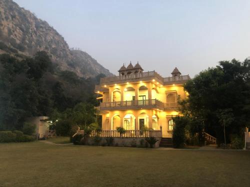 a large house with lights on in a field at Namanbagh in Alwar