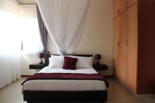 - une chambre avec un grand lit et une fenêtre dans l'établissement Signature Hotel Apartments, à Jinja