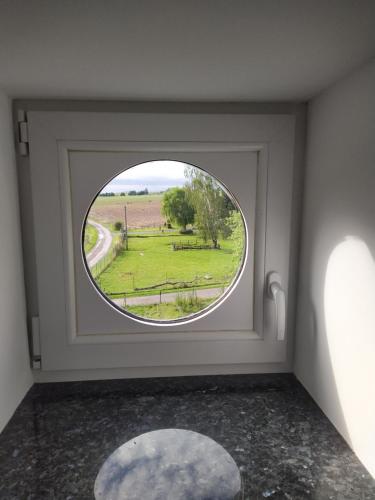 Una ventana redonda en una habitación con vistas al campo en Gîte Le Framboisier V de la distillerie Bio Spirit Belgium, en Neufchâteau