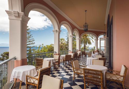 ein Restaurant mit Tischen und Stühlen auf einem Balkon in der Unterkunft Reid's Palace, A Belmond Hotel, Madeira in Funchal