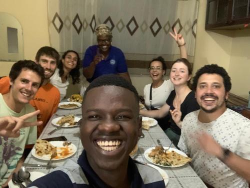 un grupo de personas sentadas alrededor de una mesa comiendo comida en JJ & JE Family House, en Dar es Salaam