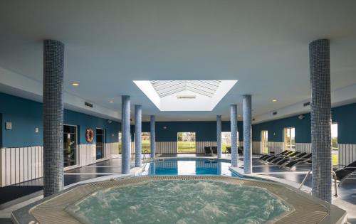 una piscina cubierta con bañera de hidromasaje en el centro de un edificio en Vila Gale Alentejo Vineyard - Clube de Campo, en Albernoa