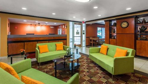 eine Lobby mit grünen Sofas und orangefarbenen Kissen in der Unterkunft Studios & Suites 4 Less Charlotte in Charlotte