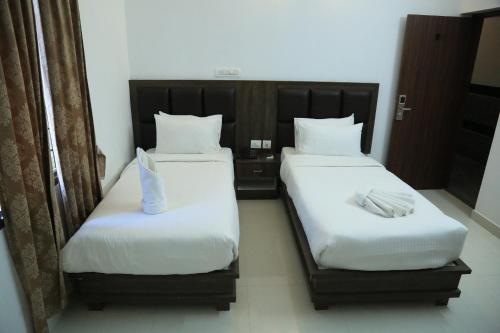 two beds in a hotel room with white sheets at CHRISTIAN GUEST HOUSE in Vellore