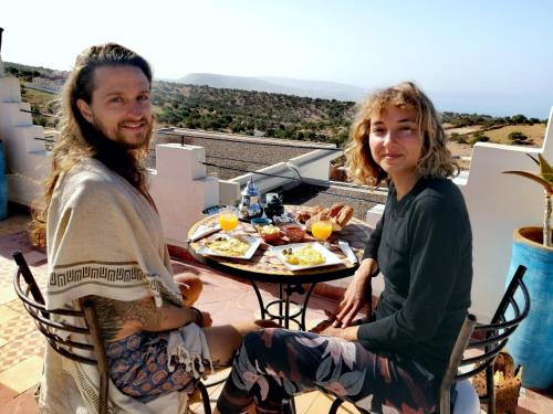 Tiguemmi nʼAït BihiTigmi surf morocco的坐在餐桌旁吃饭的男人和女人