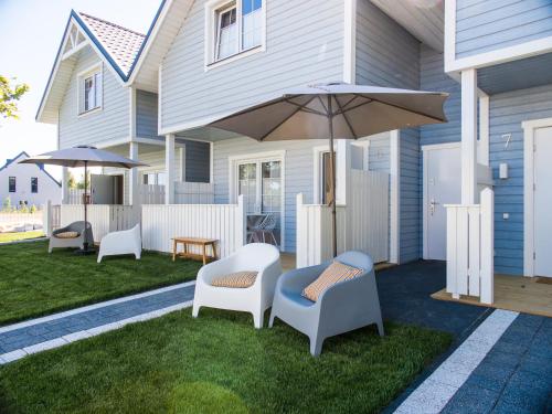 een patio met een tafel en stoelen en een parasol bij Holiday Bay in Władysławowo