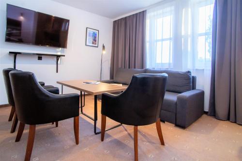 ein Wohnzimmer mit einem Tisch, Stühlen und einem Sofa in der Unterkunft Warsaw Apartments - Apartamenty Sadyba in Warschau