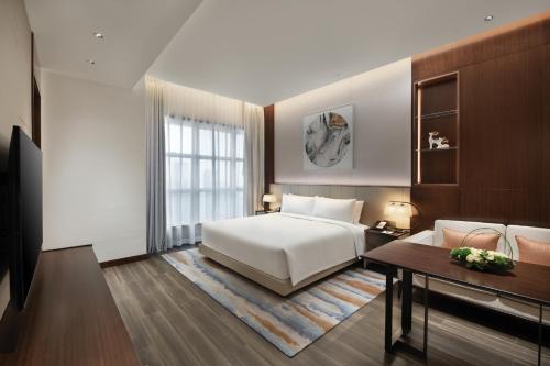 - une chambre avec un lit, une table et un canapé dans l'établissement Oakwood Residence Foshan, à Foshan