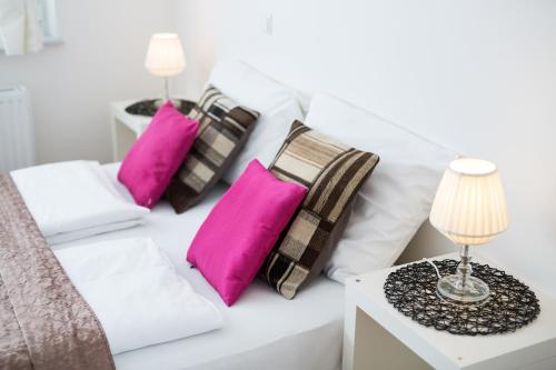 a white bed with pink pillows and a table with a lamp at Bled Apartments in Bled