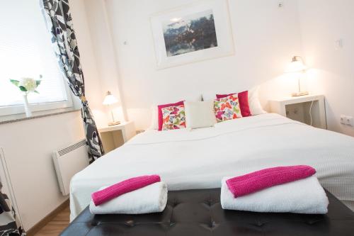 a bedroom with a large white bed with pink pillows at Bled Apartments in Bled