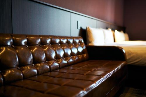 a brown leather couch in a hotel room with a bed at Rakuten STAY Kokura Station Standard Twin Room with counter table in Kitakyushu