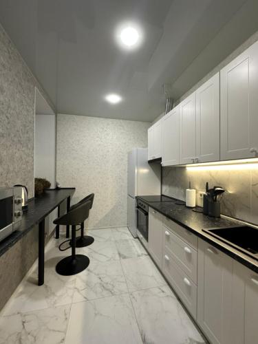 a kitchen with white cabinets and a chair in it at Апартаменты Well - Being in Umanʼ