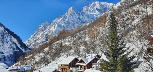 um alojamento de esqui com montanhas cobertas de neve ao fundo em Hotel Dente Del Gigante em Courmayeur