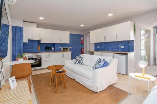 a living room with a white couch and a kitchen at Setúbal Downtown Blue in Setúbal