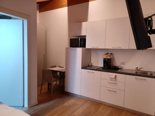 a small kitchen with white cabinets and a table at Superior Beach Aparthotel in Lido di Jesolo