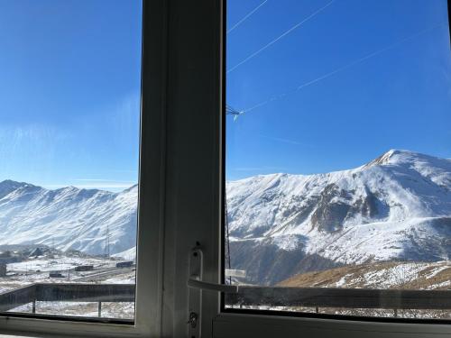 a view of a snowy mountain from a window at YETI-clubcom in Gudauri