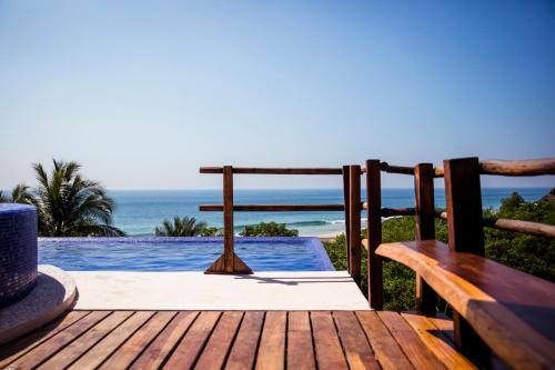 een houten terras met uitzicht op de oceaan bij Hotel El Copal in Mazunte