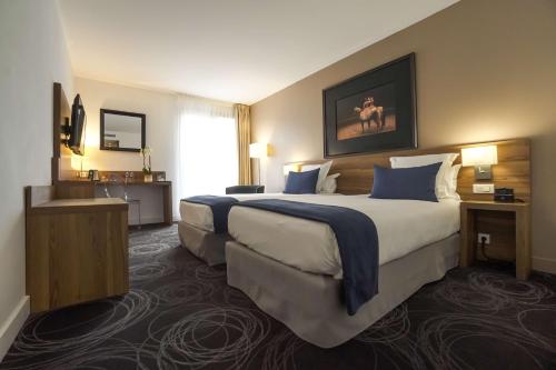 een grote hotelkamer met 2 bedden en een raam bij Best Western Plus Hotel Du Parc Chantilly in Chantilly