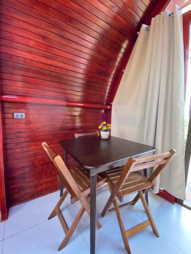 una mesa y sillas en una habitación con una pared de madera en Glamping Campo Alegre, en Cartago