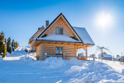 uma cabana de madeira na neve com neve à sua volta em Domki w Mizernej 38, Czorsztyn , Pieniny, Szczawnica em Kluszkowce