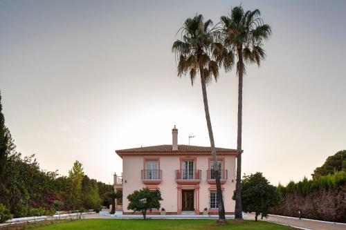 une maison avec deux palmiers devant elle dans l'établissement Villa Triana4, à Valencina de la Concepción