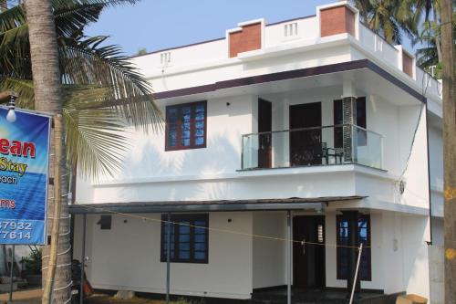 a white house with a palm tree in front of it at ENOCEAN HOMESTAY in Cherai Beach